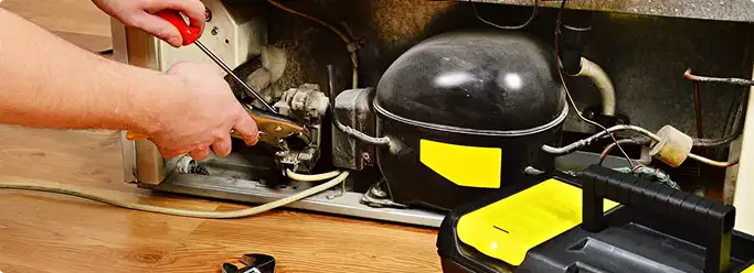 Refrigerator repair technician fixing the compressor and wiring in San Elizario, TX