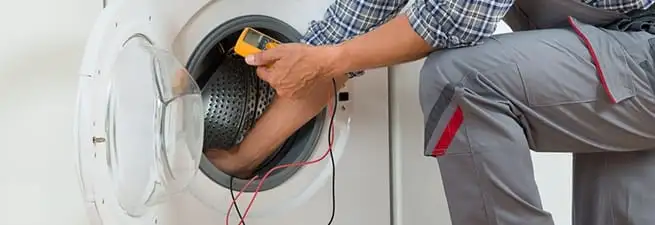 Dryer repair technician inspecting and repairing a clothes dryer in El Paso, TX