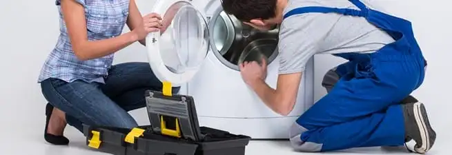 Washer repair technician inspecting a front-load washing machine with tools in El Paso, TX