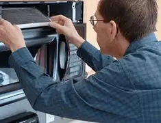Appliance repair technician replacing a microwave vent filter in El Paso, TX