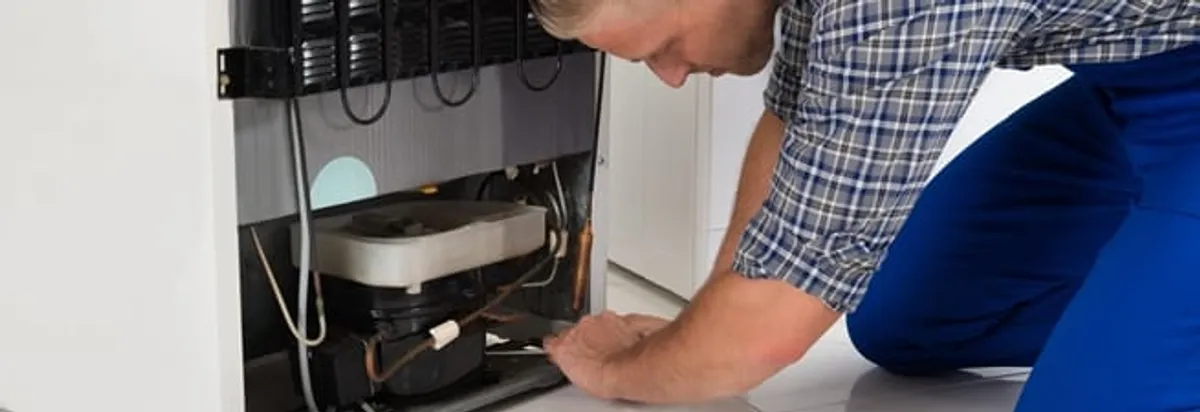 Refrigerator repair technician servicing the compressor and condenser area in El Paso, TX
