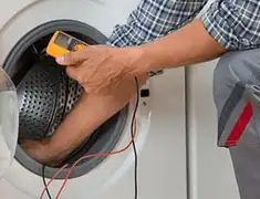 Washing machine repair technician testing a front-load washer with diagnostic tools in El Paso, TX