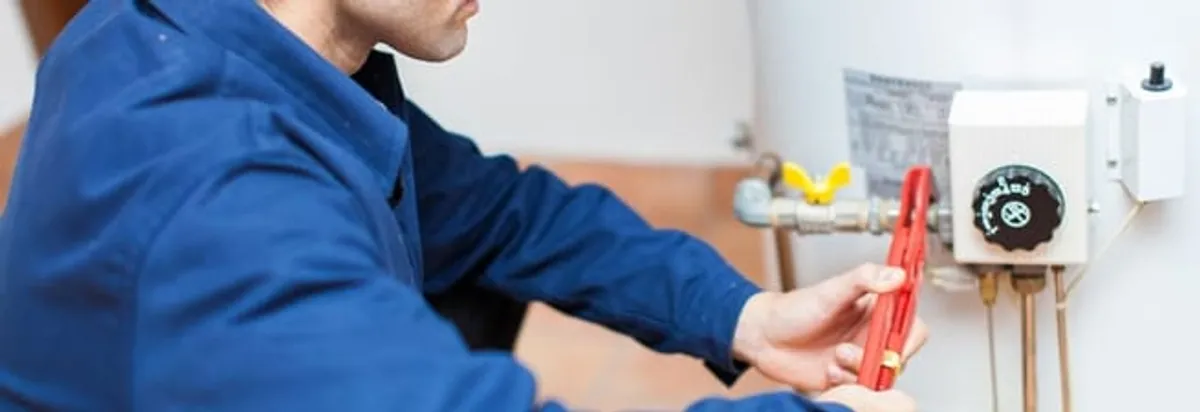 Water heater repair technician adjusting the temperature control and gas valve in El Paso, TX